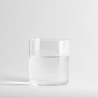 Vaso transparente cilíndrico de cristal que contiene agua, sobre fondo blanco uniforme