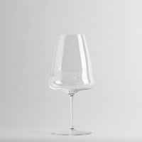 Transparent wine glass with slim stem on uniform white background