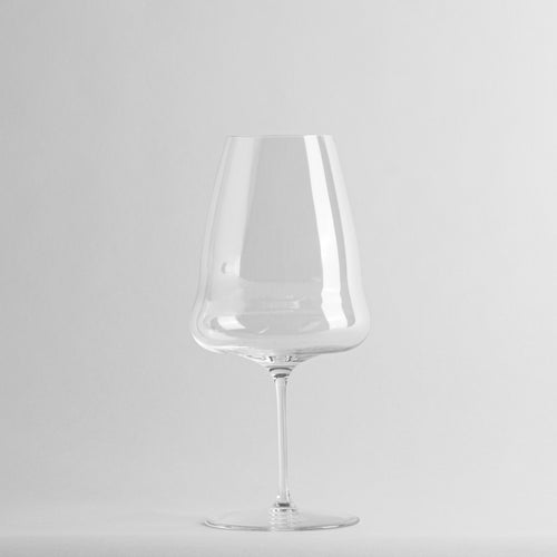 bicchiere da vino trasparente in vetro con gambo sottile su sfondo bianco uniforme