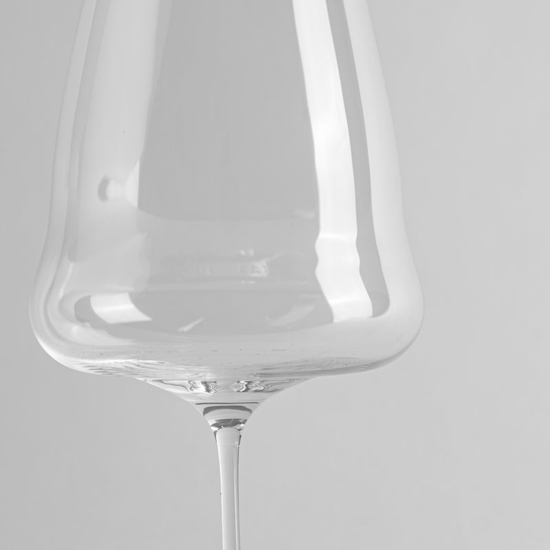 Transparent stem glass with slim stem on light grey background