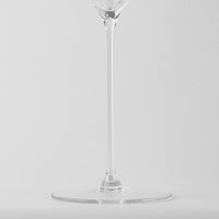 Copa de vino de vidrio transparente con tallo largo y base redonda plana sobre fondo gris claro