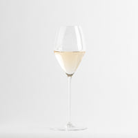 Copa de vino blanco transparente con líquido amarillo pálido sobre fondo blanco