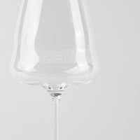 Verre à vin en verre transparent à tige fine sur fond clair uniforme.