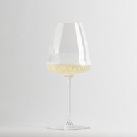 Verre transparent en verre avec light champagne et bulles sur fsurd blanc.