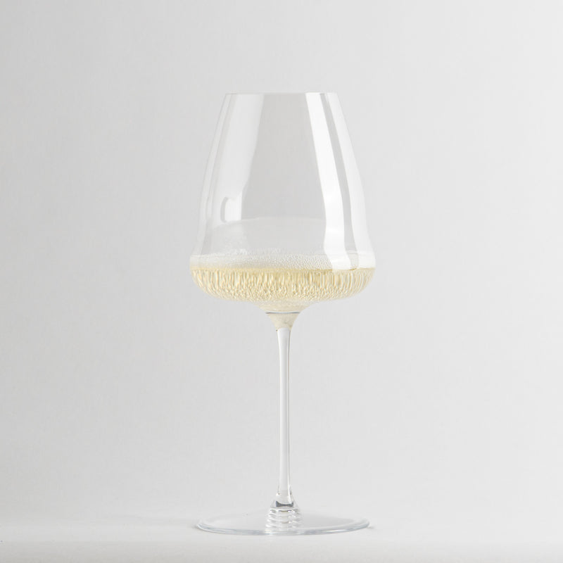 Verre transparent en verre avec light champagne et bulles sur fsurd blanc.