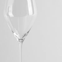 calice di vetro trasparente con gambo sottile su sfondo grigio chiaro