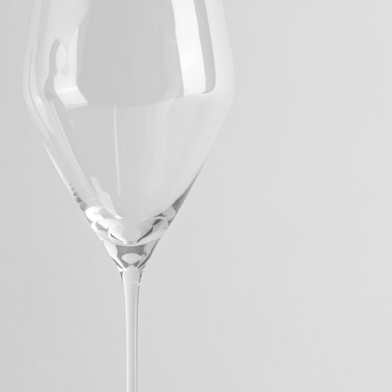 calice di vetro trasparente con gambo sottile su sfondo grigio chiaro