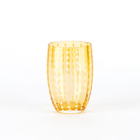 Cylindrical glass tumbler in glass transparent orange with decorazioni of punti bianchi verticali, on neutral white background.