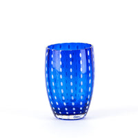 Glass tumbler blue transparent with white dot decorations, rounded cylindrical shape, transparent bottom, white background.