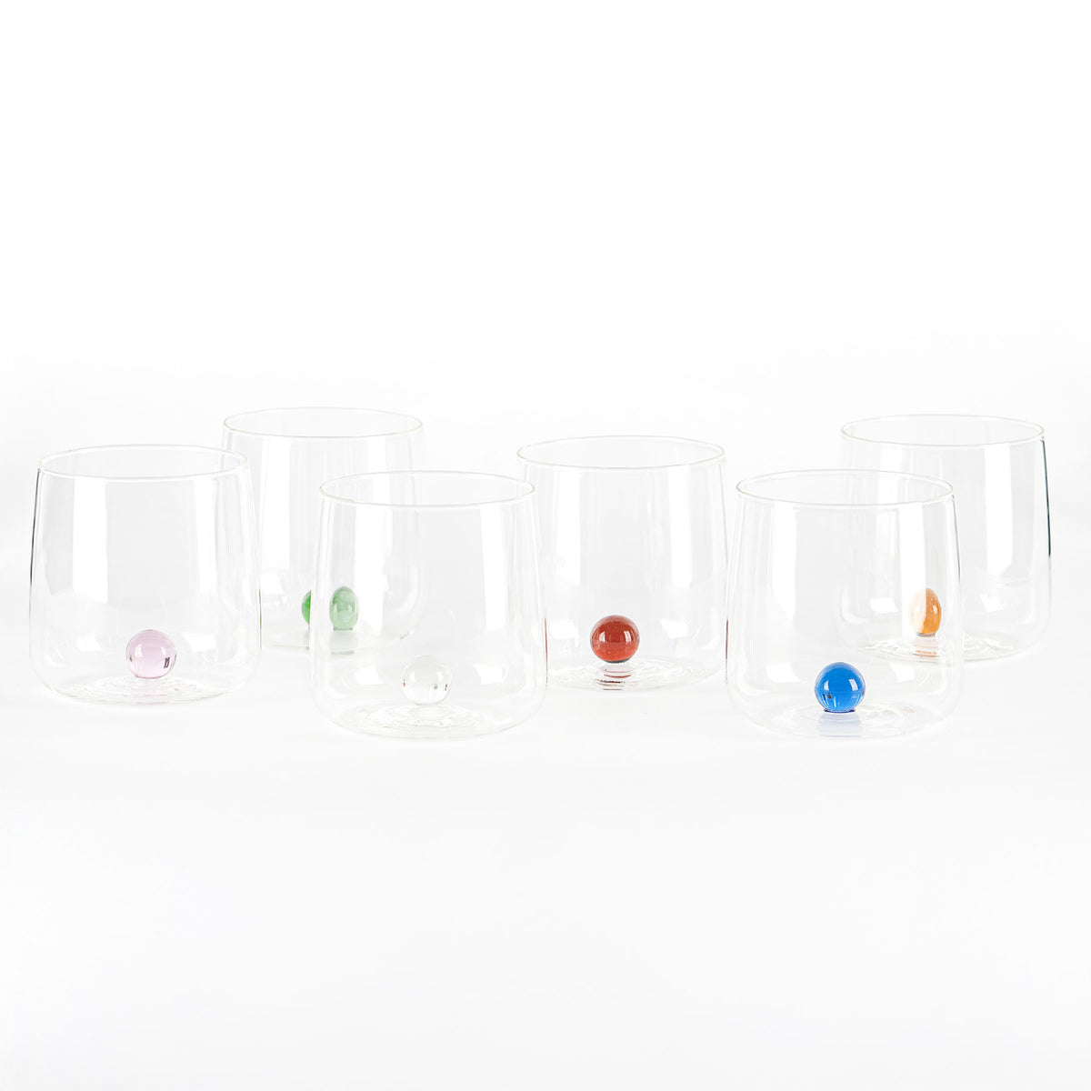 Set di sei bicchieri in vetro trasparente con base sferica colorata, su sfondo bianco.