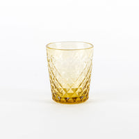 Verre ambré avec motif ajouré en forme de losanges et base épaisse sur fond blanc