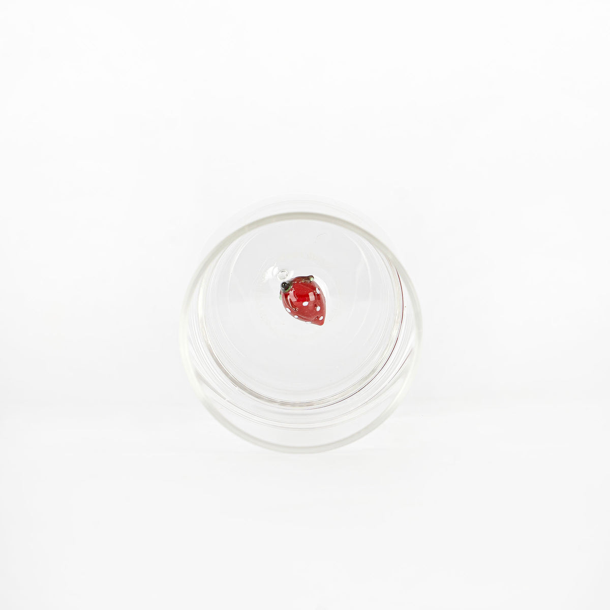 bicchiere di vetro trasparente con coccinella rossa decorativa in vetro al centro, sfondo bianco uniforme