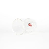 bicchiere di vetro trasparente con decorazione interna a forma di fragola rossa con puntini bianchi su sfondo bianco