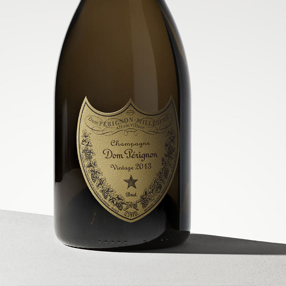 bottiglia di champagne Dom Pérignon Vintage 2013 in vetro scuro con etichetta dorata su sfondo chiaro minimalista