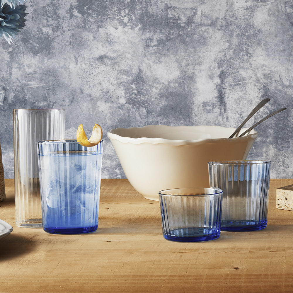 Set di quattro bicchieri in vetro smerigliato color blu e trasparente con superfici rigate, alcuni con ghiaccio e scorza di limone, su