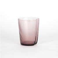 Vaso transparente rosa con superficie estriada y apertura con pequeña muesca, sobre fondo blanco.