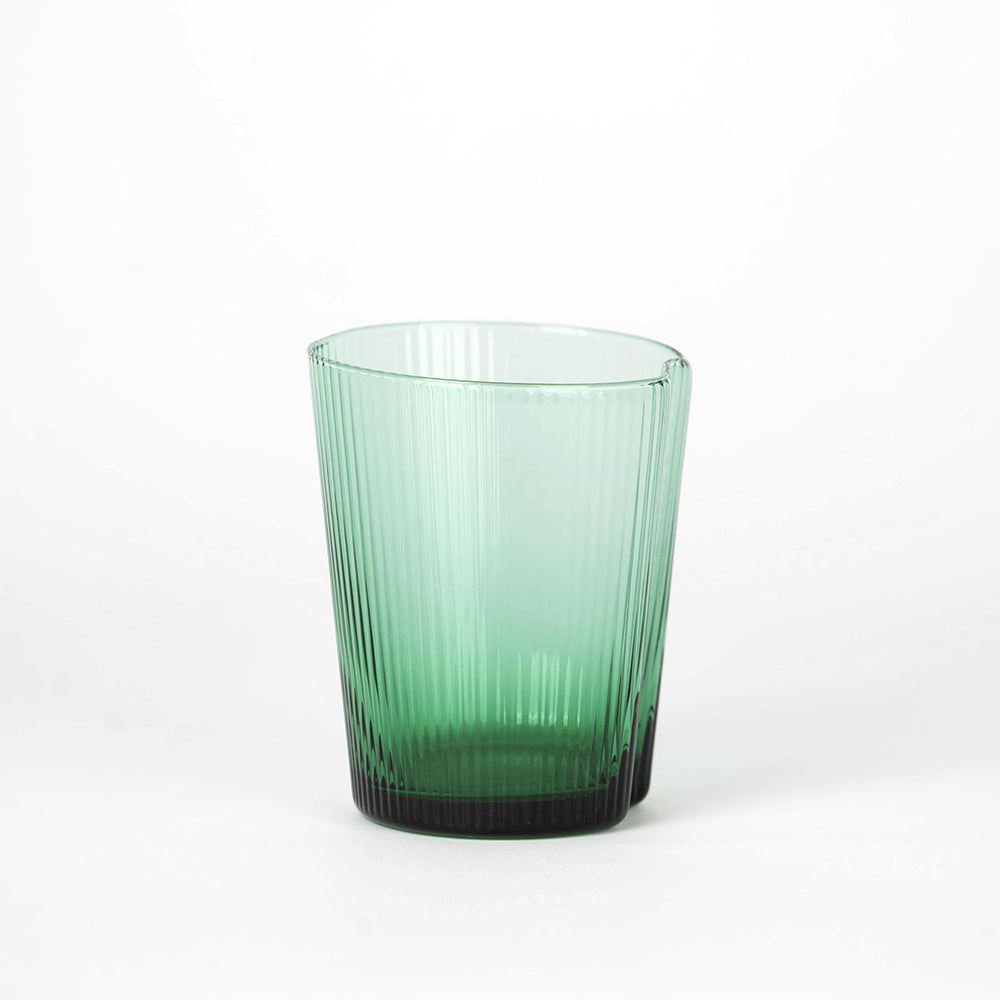Vaso de cristal verde degradado con superficie estriada y borde irregular sobre fondo blanco.