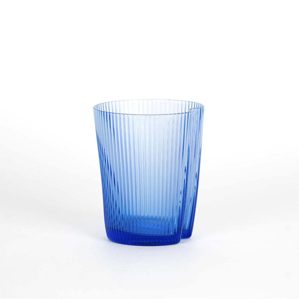 Short vaso de vidrio de vidrio azul transparente csobre vertical fluted surface, sobre fsobredo blanco.