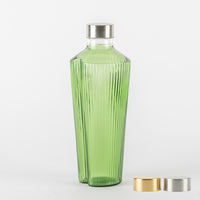 Grüne Glasflasche mit geriffelter Oberfläche und silbernem Metallverschluss, daneben zwei runde gold- und silberfarbene Verschlüsse, weißer Hintergrund.