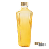 Winklige transparente Plastikflasche mit gelber Flüssigkeit, goldenem Verschluss und goldenen und silbernen Metallverschlüssen daneben.