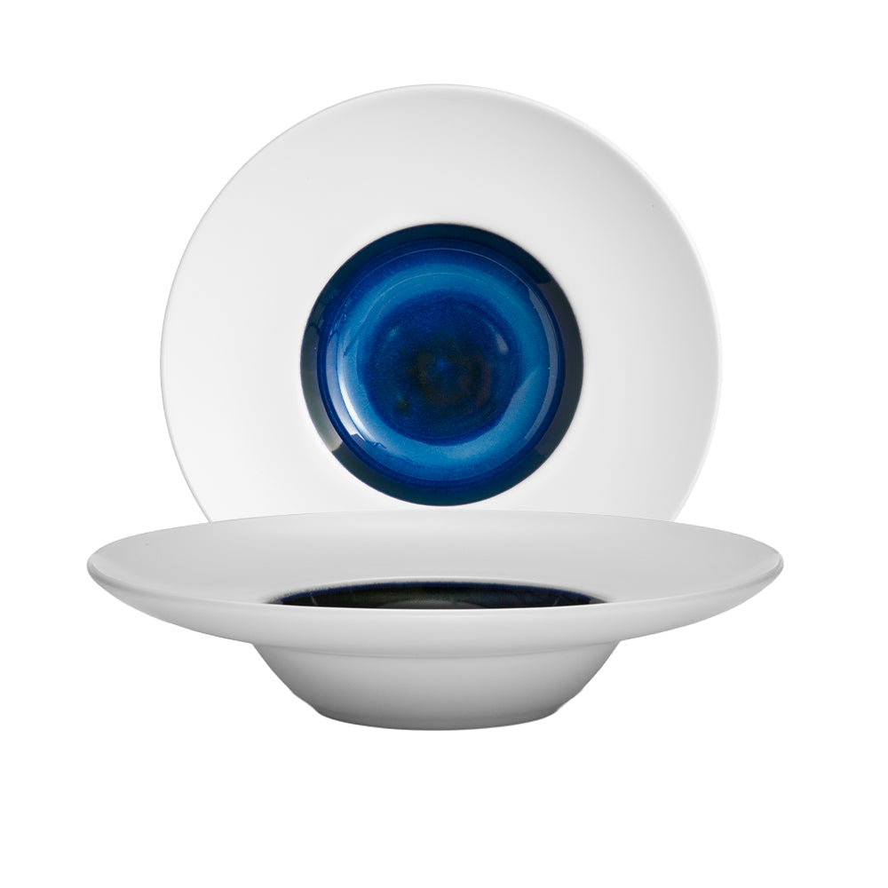 two white ceramic plates with blue and black glazed interior in concentric circles on white background