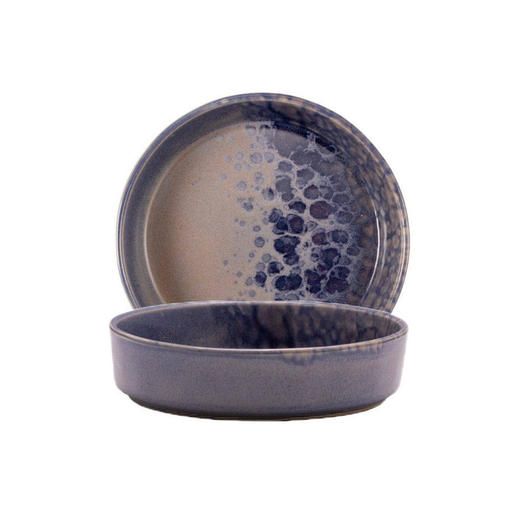 Due piatti in ceramica smaltata, tondi, con decorazione a macchie blu su sfondo beige e blu in ambiente neutro.