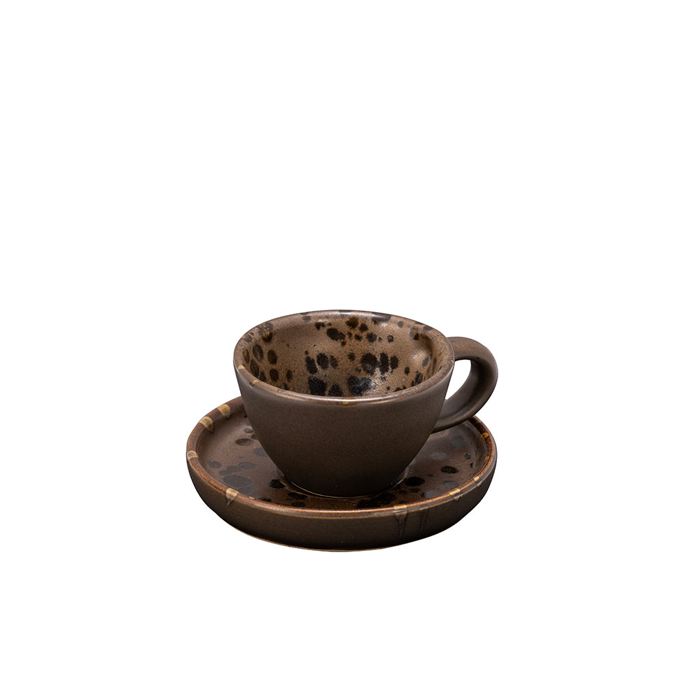 Tazza con piattino in ceramica marrone con decorazioni maculate nere all'interno e sulla superficie del piattino.