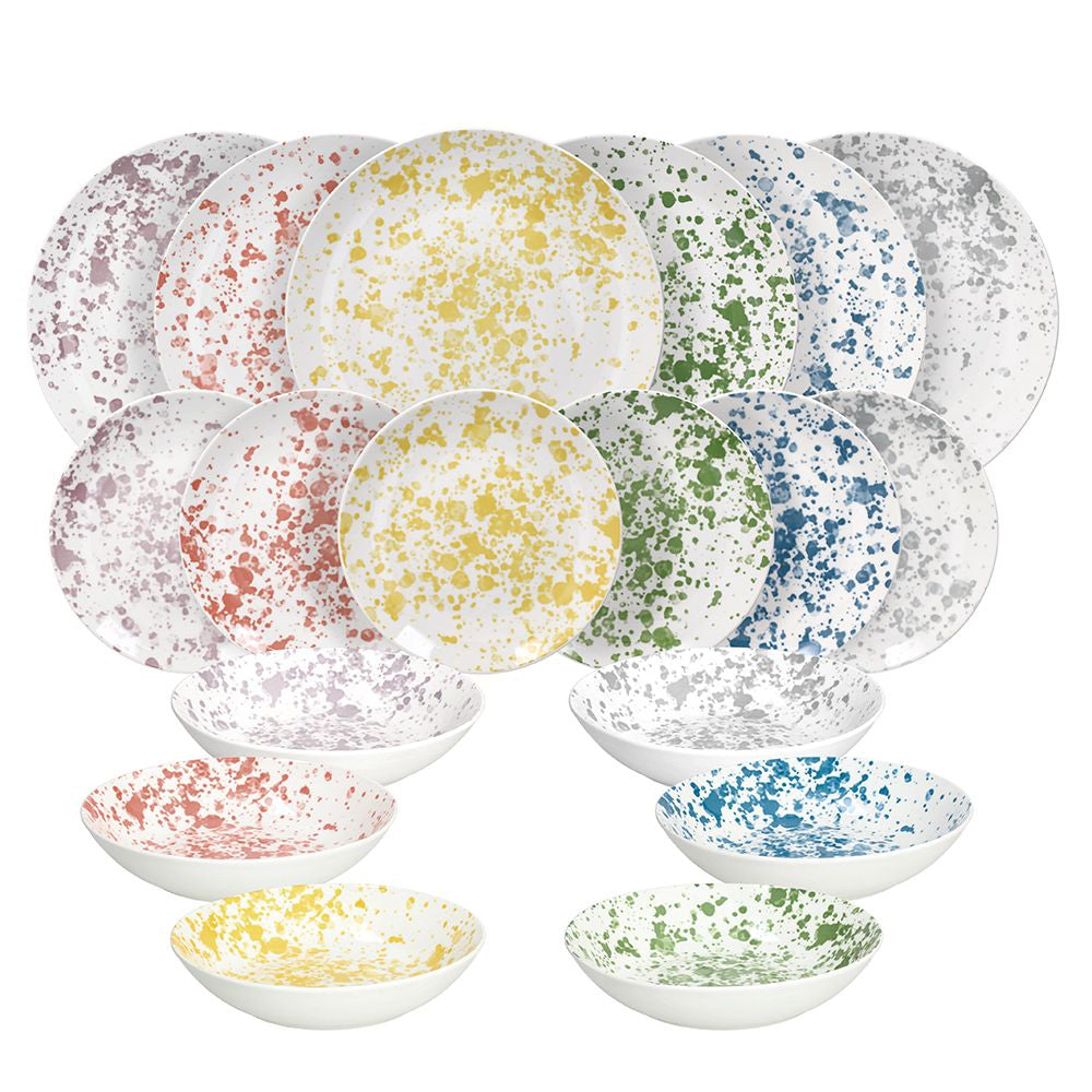 Set di 18 piatti in ceramica bianca con macchie colorate gialle, verdi, blu, rosse, viola e grigie, di varie dimensioni.