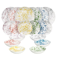 Set di 18 piatti in ceramica bianca con macchie colorate gialle, verdi, blu, rosse, viola e grigie, di varie dimensioni.