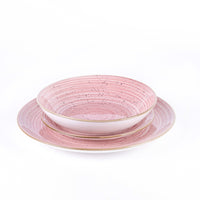 Dos platos de cerámica, uno sobre otro, de color rosa con vetas y puntitos negros, borde dorado. Fondo blanco.