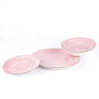 Tres platos de cerámica rosa con detalles en espiral, uno plano y dos ligeramente curvados, con borde dorado.