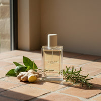 Clear bottle with light liquid CULTI MILANO MAREMINERALE label, ginger, lime and rosemary sprig on terracotta floor.
