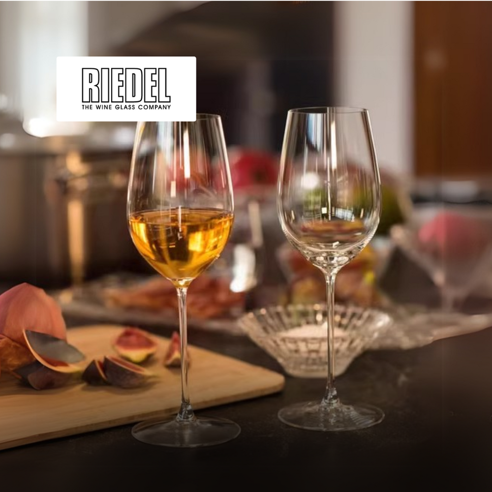 due calici di vino in vetro trasparente, uno con vino bianco dorato e uno vuoto, su tavolo con frutta e