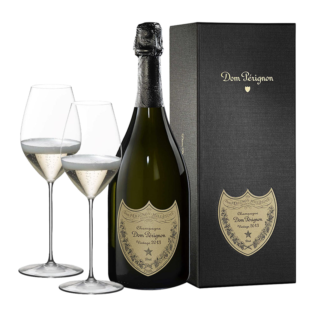 Bottiglia di champagne Dom Pérignon Vintage 2013 verde scuro con etichetta beige, confezione rigida nera e due calici con bollicine.