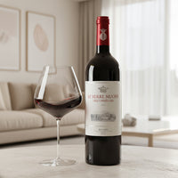 bottiglia di vino rosso Le Serre Nuove dell'Ornellaia 2021 con bicchiere parzialmente pieno su tavolo in ambiente soggiorno luminoso colore beige