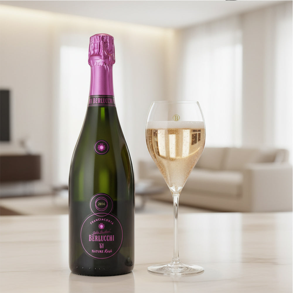 Berlucchi 61 mousserende wijnfles met roze dop, naast een wijnglas met bubbels, op een tafel in een lichte omgeving.