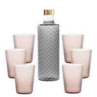 Botella transparente con tapón dorado rodeada de seis copas rosas, todas con superficie de rombos.