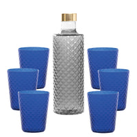 Botella de vidrio transparente con tapón dorado, rodeada de seis copas azules con superficie piramidal.
