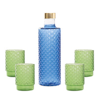 Bottiglia blu con tappo dorato e quattro bicchieri verdi con texture a rilievo, su sfondo bianco.