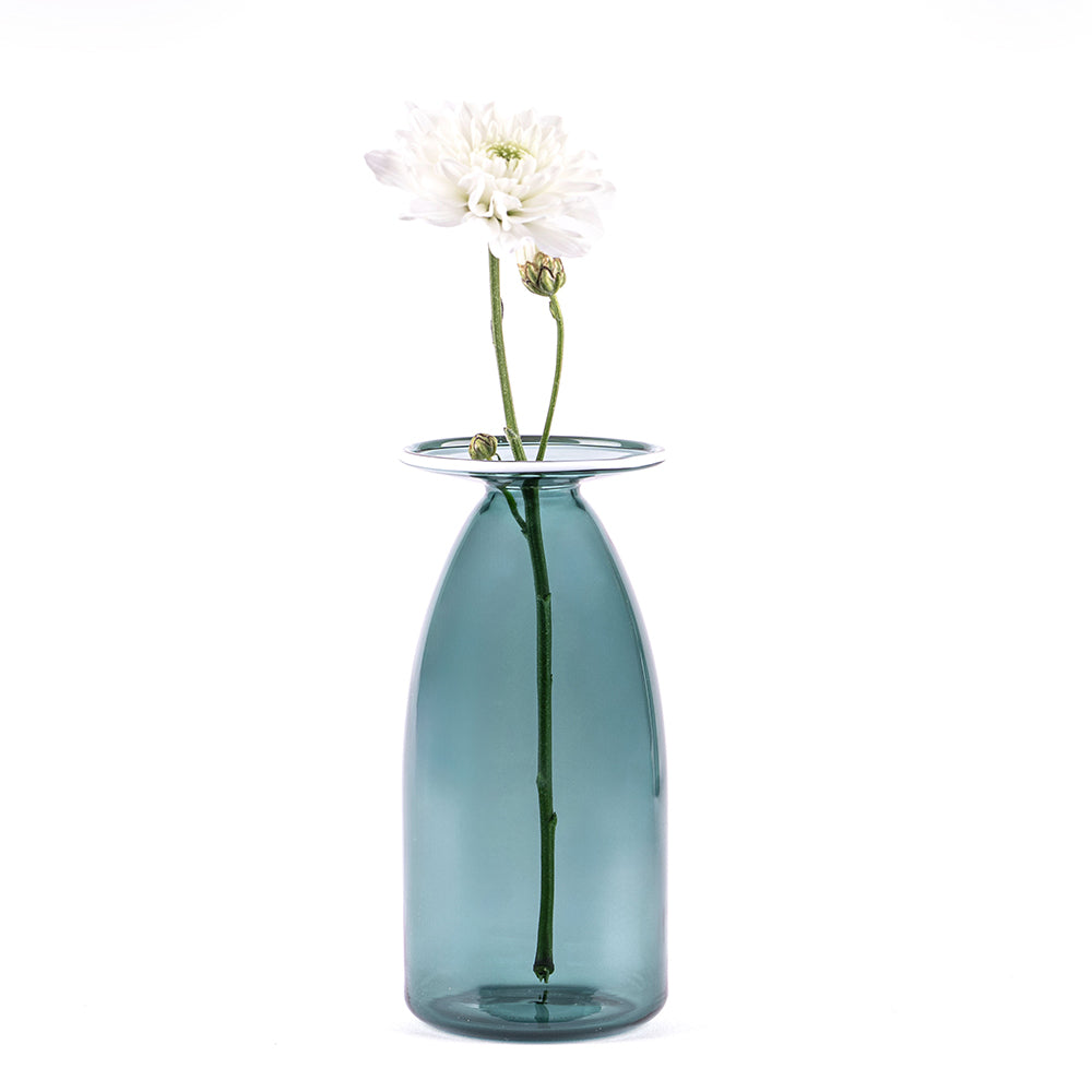 vase en verre bleu clair transparent avec fleur blanche et deux boutons sur fond blanc