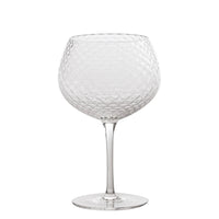Verre à vin en verre transparent à texture losangée, longue tige et base ronde plate sur fond blanc.