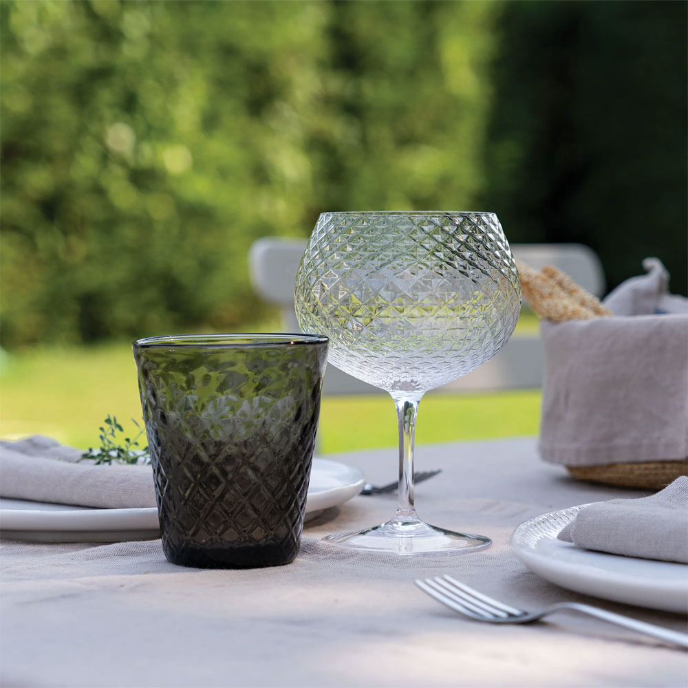 eau glass en verre dark vert et verre à vin in transparent glass avec faceted surface sur outdoor set table