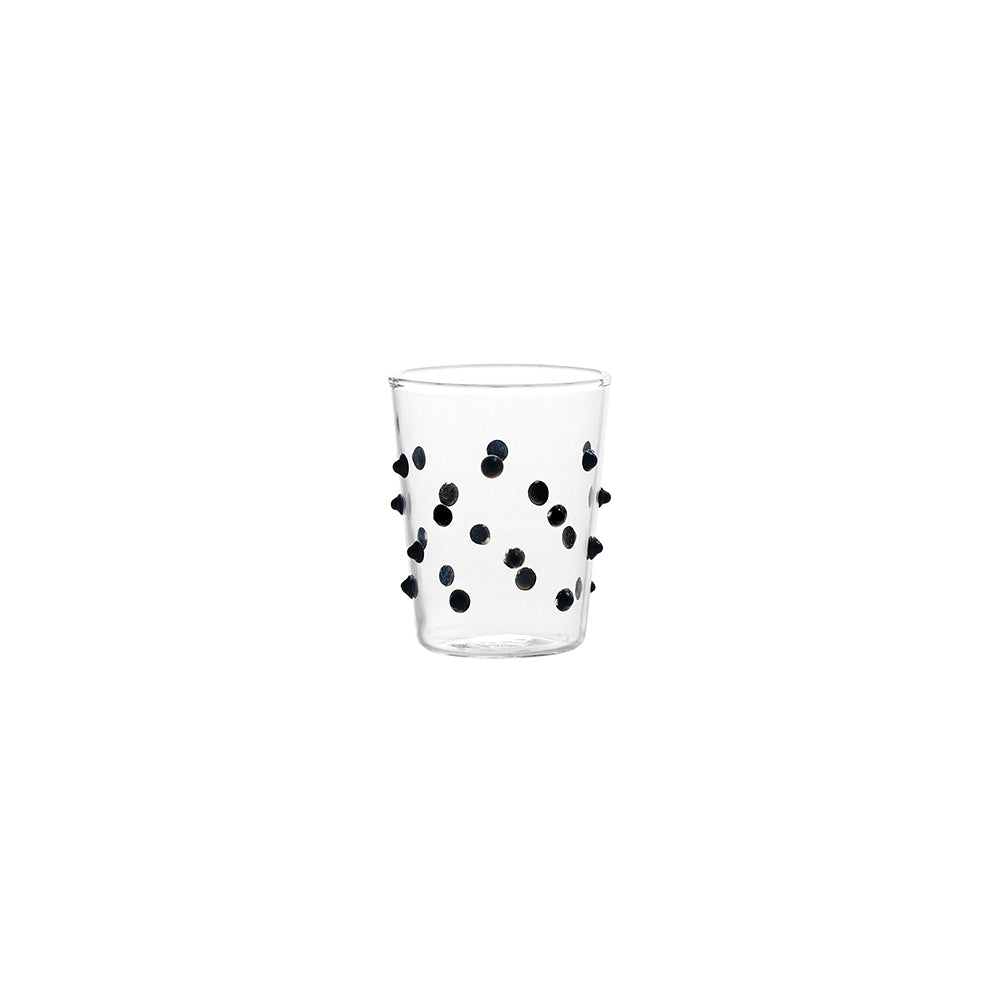Verre transparent en verre avec petits reliefs circulaires noirs distribués sur toute la surface, fond blanc.