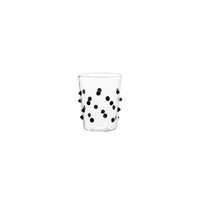 Verre transparent en verre avec petits reliefs circulaires noirs distribués sur toute la surface, fond blanc.