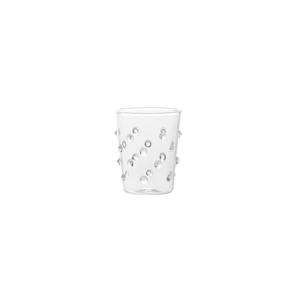 Verre transparent en verre avec reliefs ronds disposés en spirale sur fond blanc.