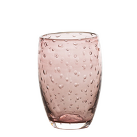 Bicchiere rosa trasparente con bolle in rilievo su tutta la superficie, forma leggermente arrotondata, sfondo bianco.