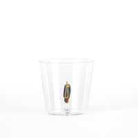 Transparent tumbler with colored figure inside, composed of blue, gold and orange details, on white background.