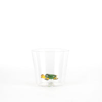 Transparent cup with a green and yellow glass turtle inside, on white background.
