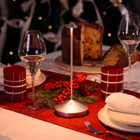 Conical silver metal table lamp on round base with glasses, Christmas decorations and panettone in the background