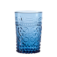 Light blue glass tumbler with embossed floral and bubble decorations, on white background.
